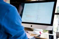 Person sits at desktop computer with code