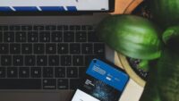 laptop keyboard and cellphone next to plant