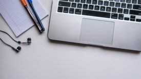 desk with laptop, notepad and headphones