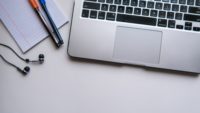 desk with laptop, notepad and headphones