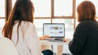 Two women using laptop together