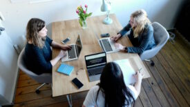 Three women sitting around table working