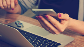 Woman holding phone in front of laptop