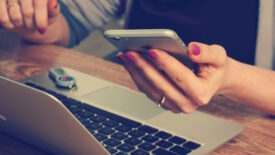 Person holding phone while using computer