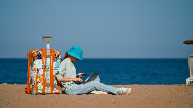 Woman with luggage and laptop on beach