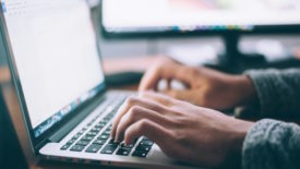 Person in denim jacket using laptop at desk