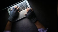 Hands wearing fingerless gloves and using laptop