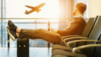 Man in airport watching airplane take off