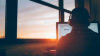 Man working on computer at sunrise