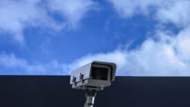 Video camera on top of building with cloudy sky behind it