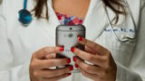 Healthcare professional with red nail polish holding cell phone