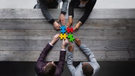 Four men putting together puzzle pieces