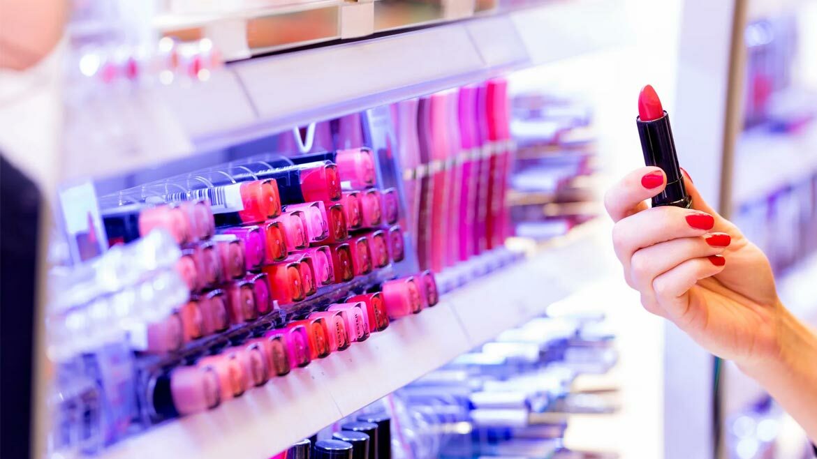 Women holding lipstick at makeup counter